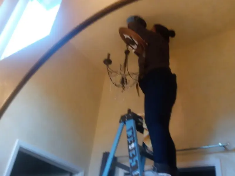Electrician installing a chandelier in a Harrison residence